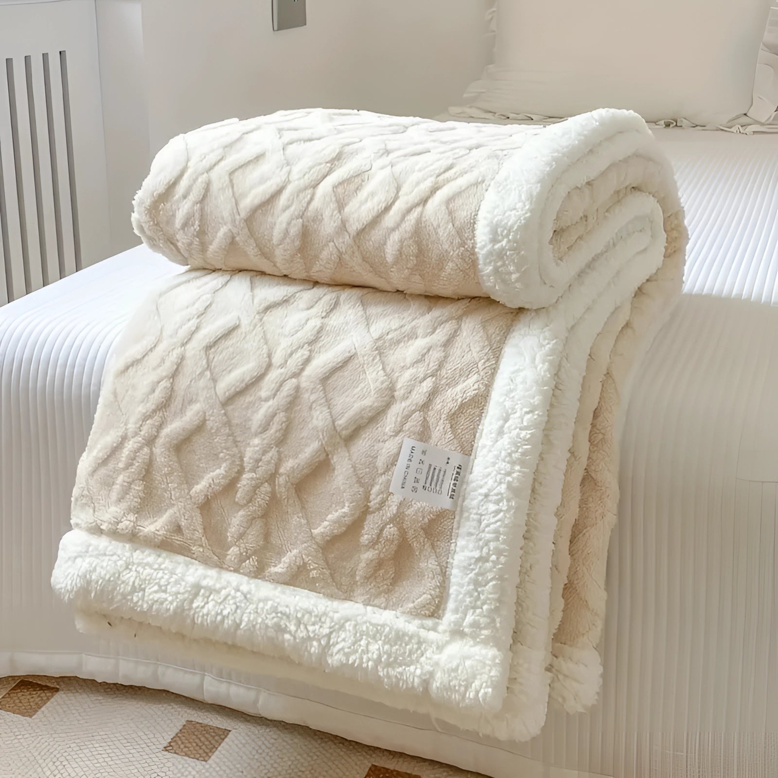 Luxurious reversible Sherpa fleece blanket in creamy white, draped elegantly over a wooden bed frame in a cozy bedroom setting, highlighting its soft texture and warm, inviting appearance, ideal for winter comfort.