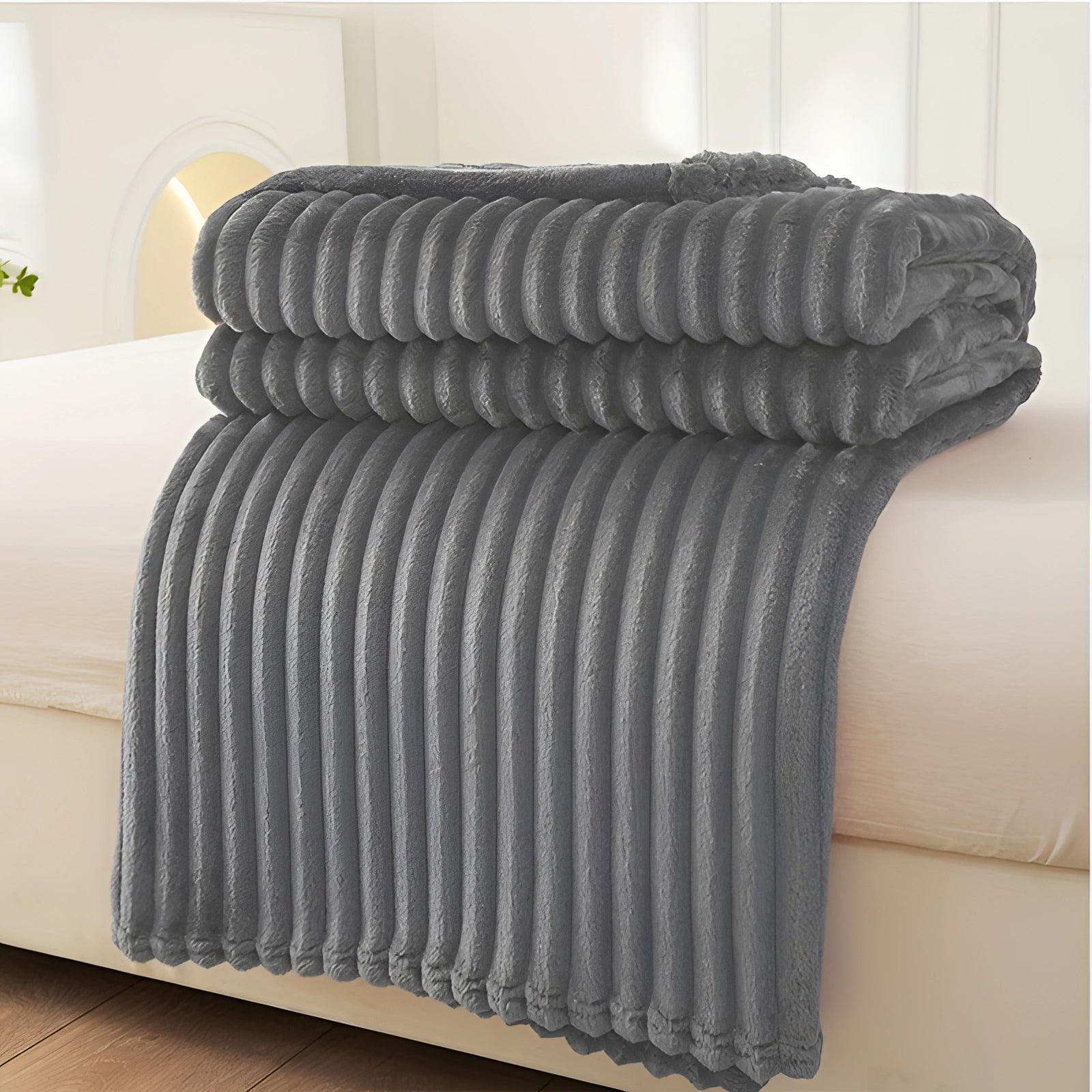 A plush gray throw blanket made of luxurious velvet material with a ribbed texture, draped elegantly over a surface, showcasing its cozy and decorative qualities.