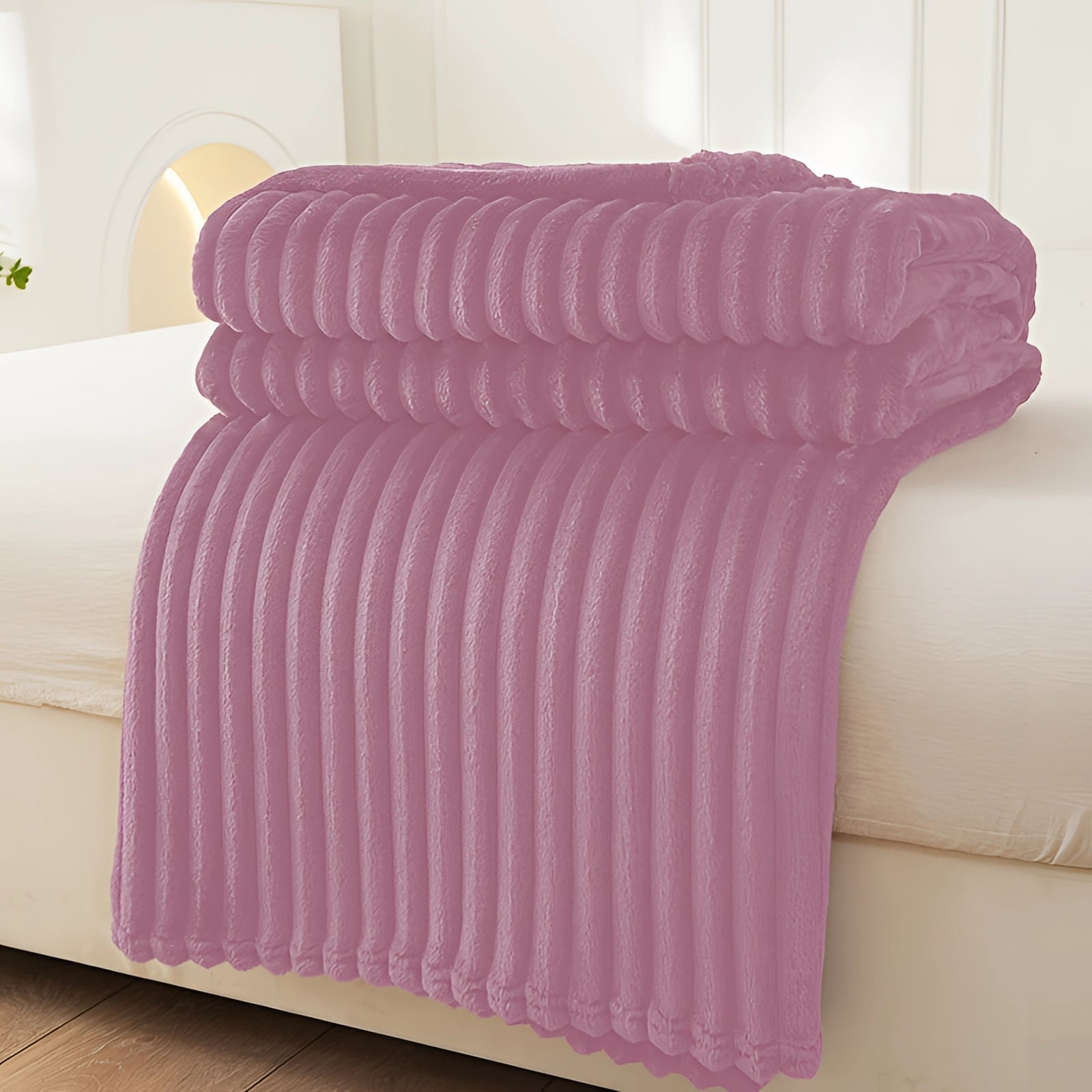 Luxurious purple velvet ribbed throw blanket draped over a wooden ottoman, adding a cozy and decorative touch to the room.