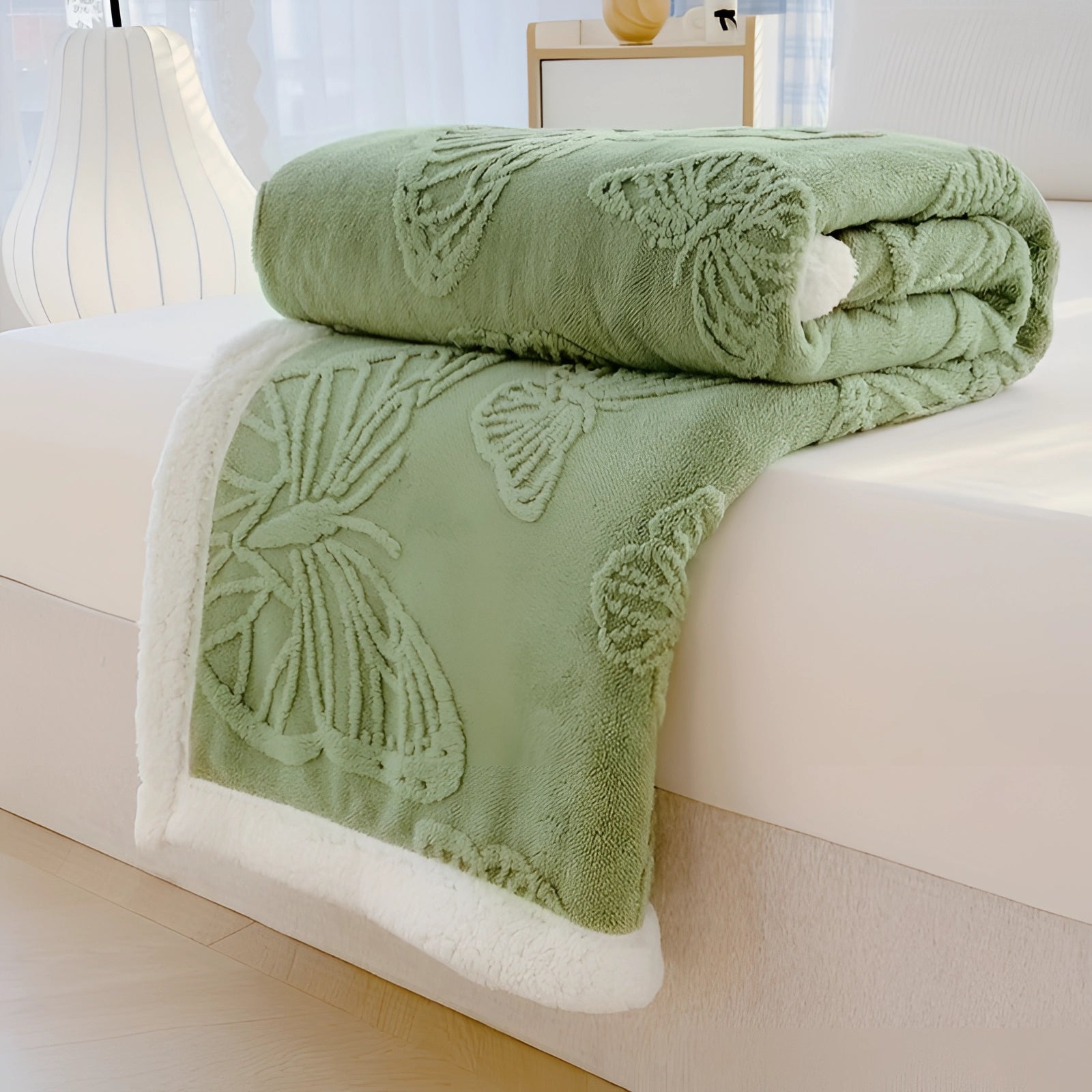 Plush sherpa fleece blanket with a gray leaves design draped over a bed in a cozy setting, accompanied by pillows, showcasing the soft and luxurious texture of the green variant measuring 200*230cm.