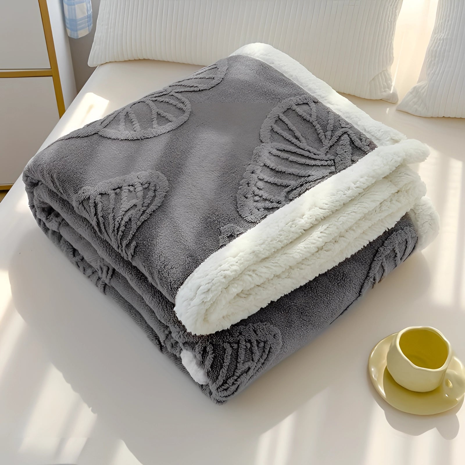 Luxury sherpa fleece blanket featuring a plush gray leaves pattern, draped over a wooden surface. The blanket has a rectangular shape and showcases a soft, comfortable textile ideal for adding warmth and style to any room.