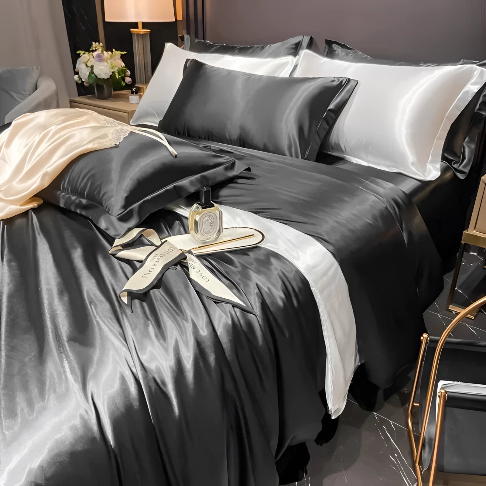 Luxurious black silk bedding set featuring satin sheets and elegant pillowcases, displayed on a neatly made bed with a wooden frame. The room is tastefully decorated with a touch of greenery, framed artwork, and an inviting atmosphere. The bedding exudes comfort and sophistication, perfectly complementing the interior design.