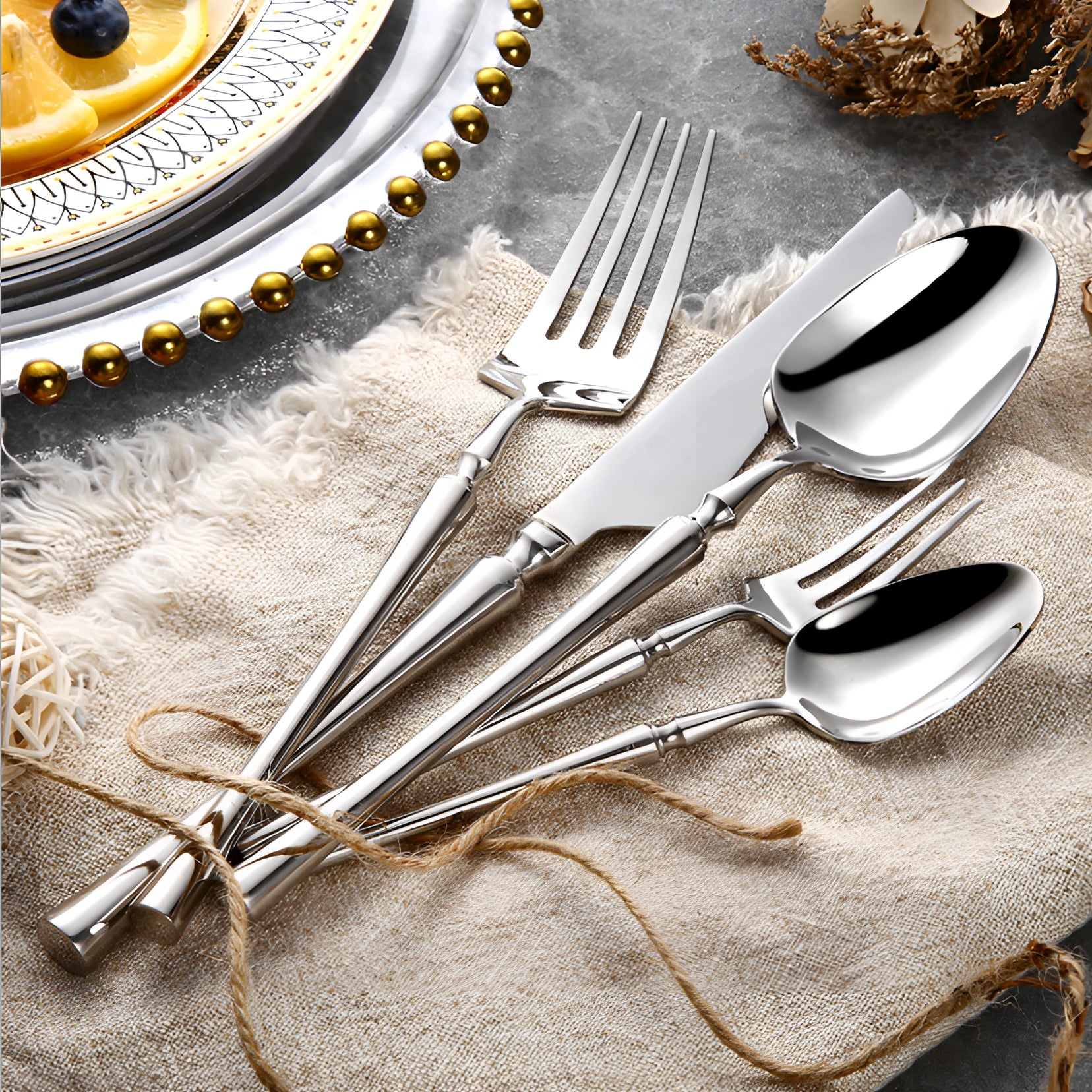 Elegant silver cutlery set featuring shiny stainless steel utensils, including forks and other tableware, elegantly arranged on a table with a white tablecloth.