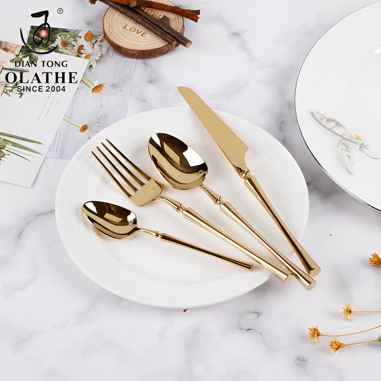 Shiny gold luxury cutlery set with elegant stainless steel silverware on a wooden table, featuring forks and other utensils arranged on a tablecloth with dishware.