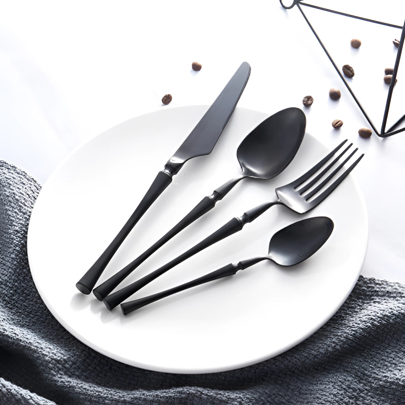 Luxury silver cutlery set displayed elegantly on a monochrome patterned plate, showcasing the sleek design and high-quality stainless steel craftsmanship.