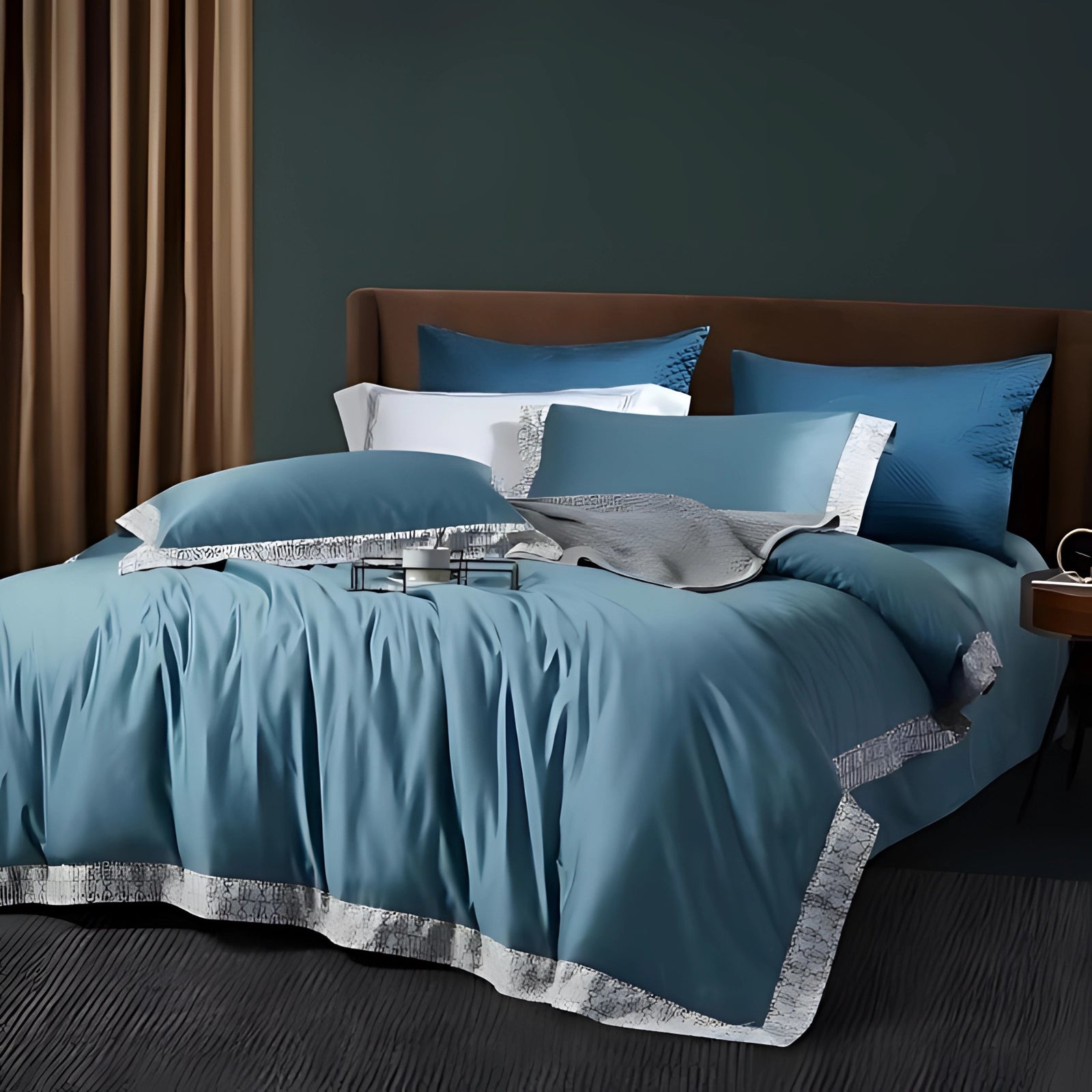 Luxury teal bedding set featuring an elegant blue comforter and pillow cases arranged on a bed frame. The scene includes a complementary grey bed skirt, creating a cozy and stylish interior design.