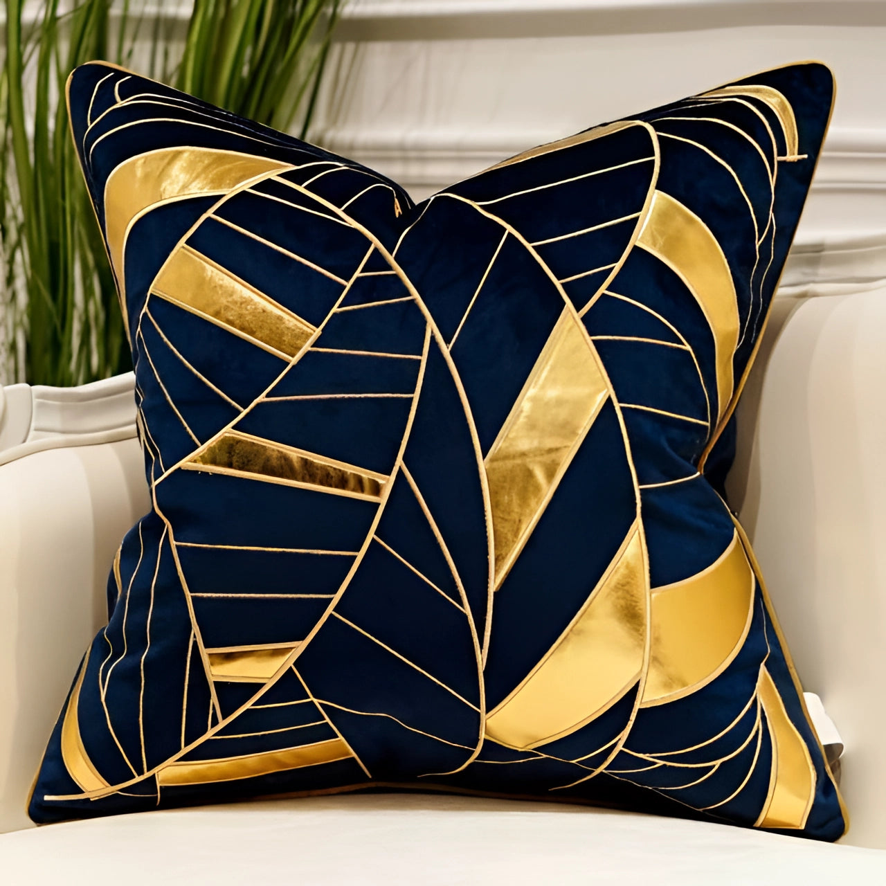 Luxurious blue velvet throw pillow with gold geometric abstract design, measuring 20" x 20", placed on a couch.