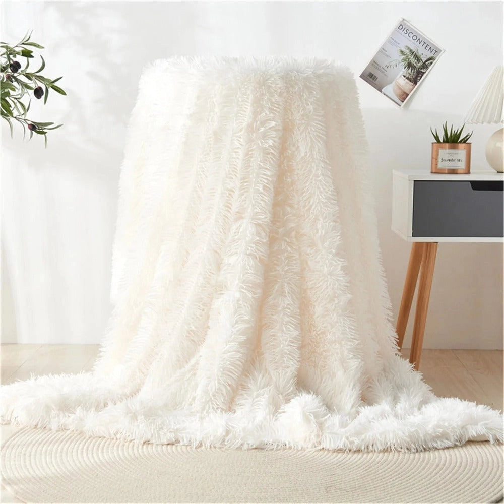 Luxurious ivory white faux fur blanket with a textured plush surface, elegantly draped over a wooden surface, creating a cozy and sophisticated atmosphere.