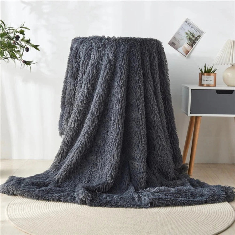 Luxurious charcoal faux fur blanket draped over a wooden floor in a stylish room, creating a cozy and elegant atmosphere.