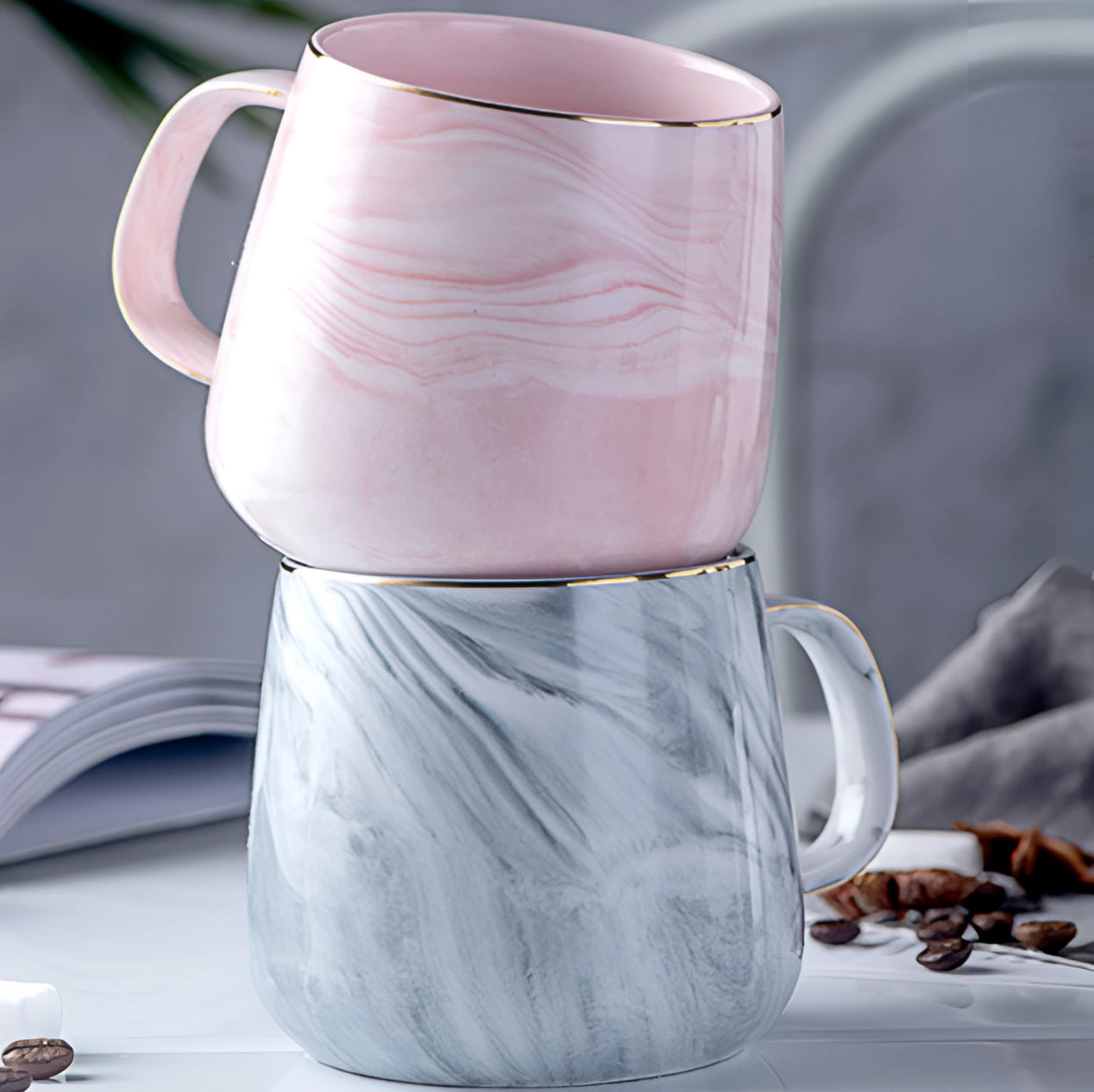 Marble coffee mug with a metallic handle, featuring a pink, grey, and white marbled design, placed on a surface.