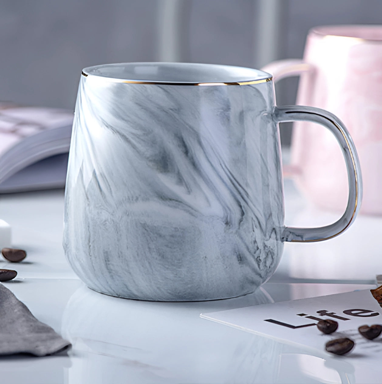 Gray marble coffee mug with a metallic handle placed on a table.