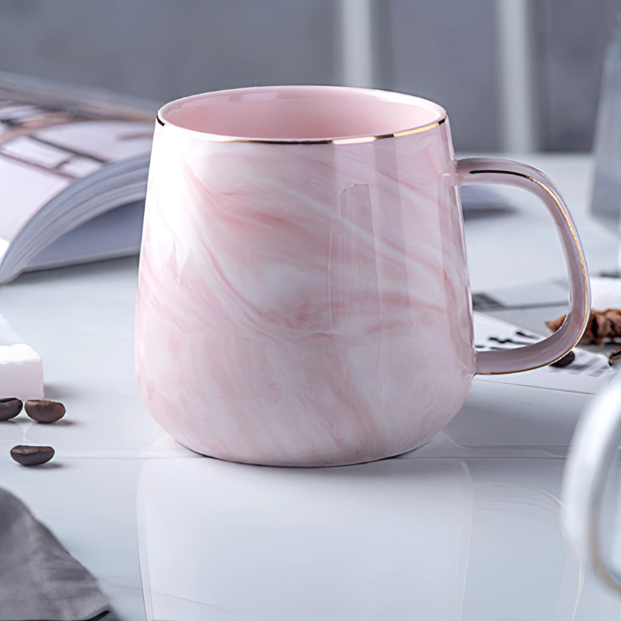 Marble coffee mug with a metallic handle in pink color, placed on a table. The mug features a marbled design and is part of tableware and drinkware collections.