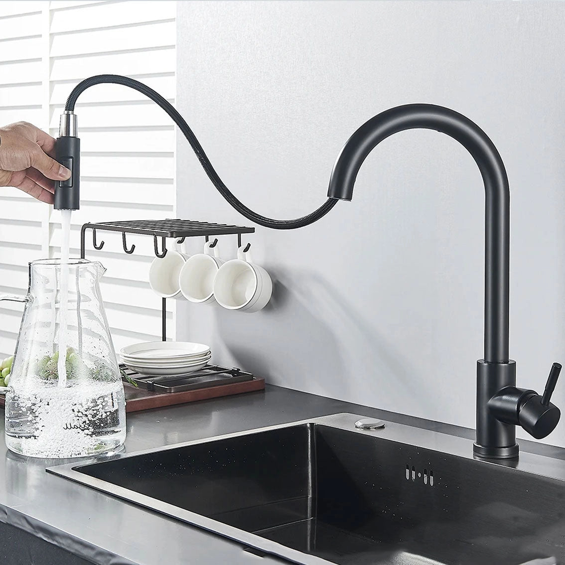 Matte black pull-down kitchen faucet with a 360° swivel spout, installed above a grey countertop in a modern kitchen setting.