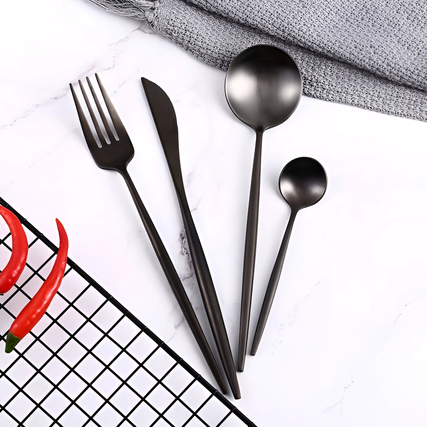 Matte black stainless steel cutlery set featuring luxury designer flatware with a sleek and modern design, including forks, knives, and spoons, arranged on a table.