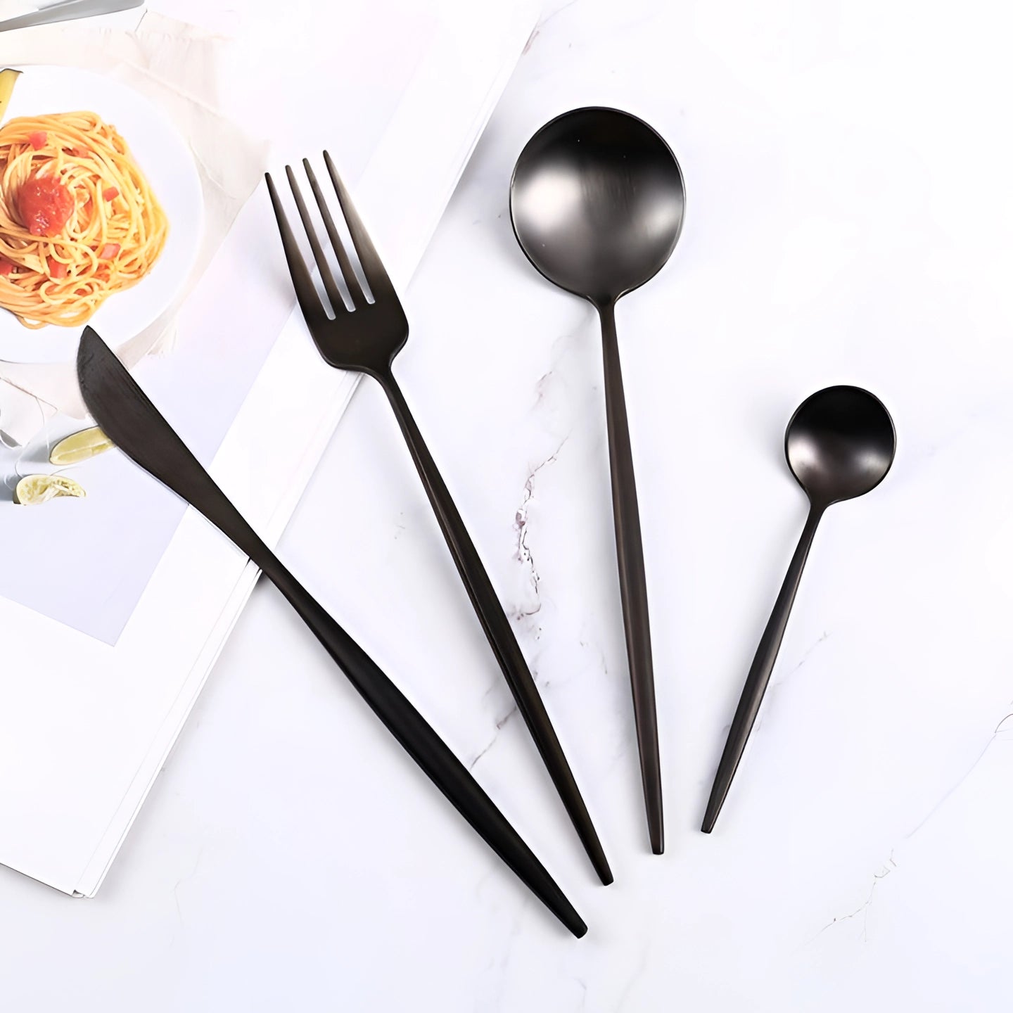 Matte black stainless steel cutlery set featuring luxury designer flatware including a spoon, displayed on a stylish table setting.