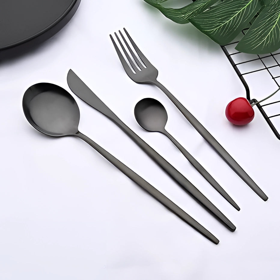 Matte black stainless steel cutlery set displayed on a table, featuring a luxury designer flatware collection with elegant patterns, arranged alongside natural elements for a stylish presentation.