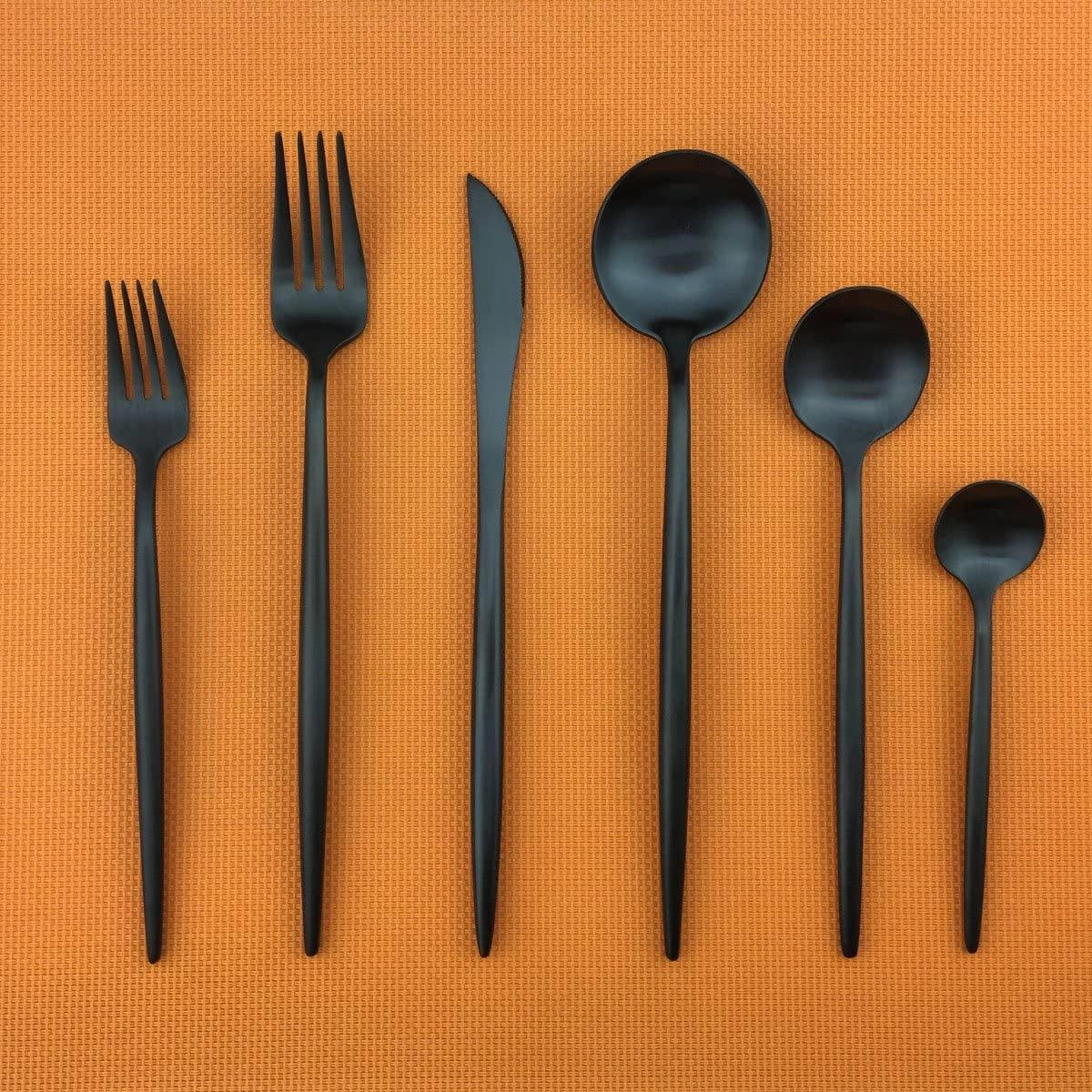 Matte black stainless steel cutlery set featuring a modern minimalist design, including a fork, displayed on a wooden surface.