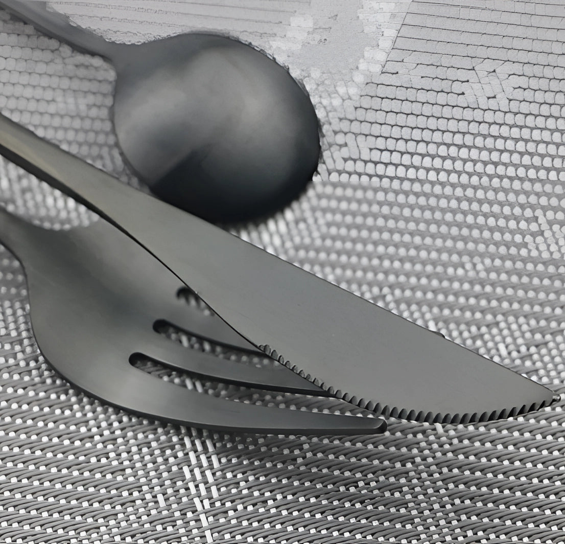 Matte black stainless steel cutlery set featuring a modern minimalist design, displayed on a grey background. The set includes a knife, fork, and spoon, showcasing sleek lines and a contemporary aesthetic.