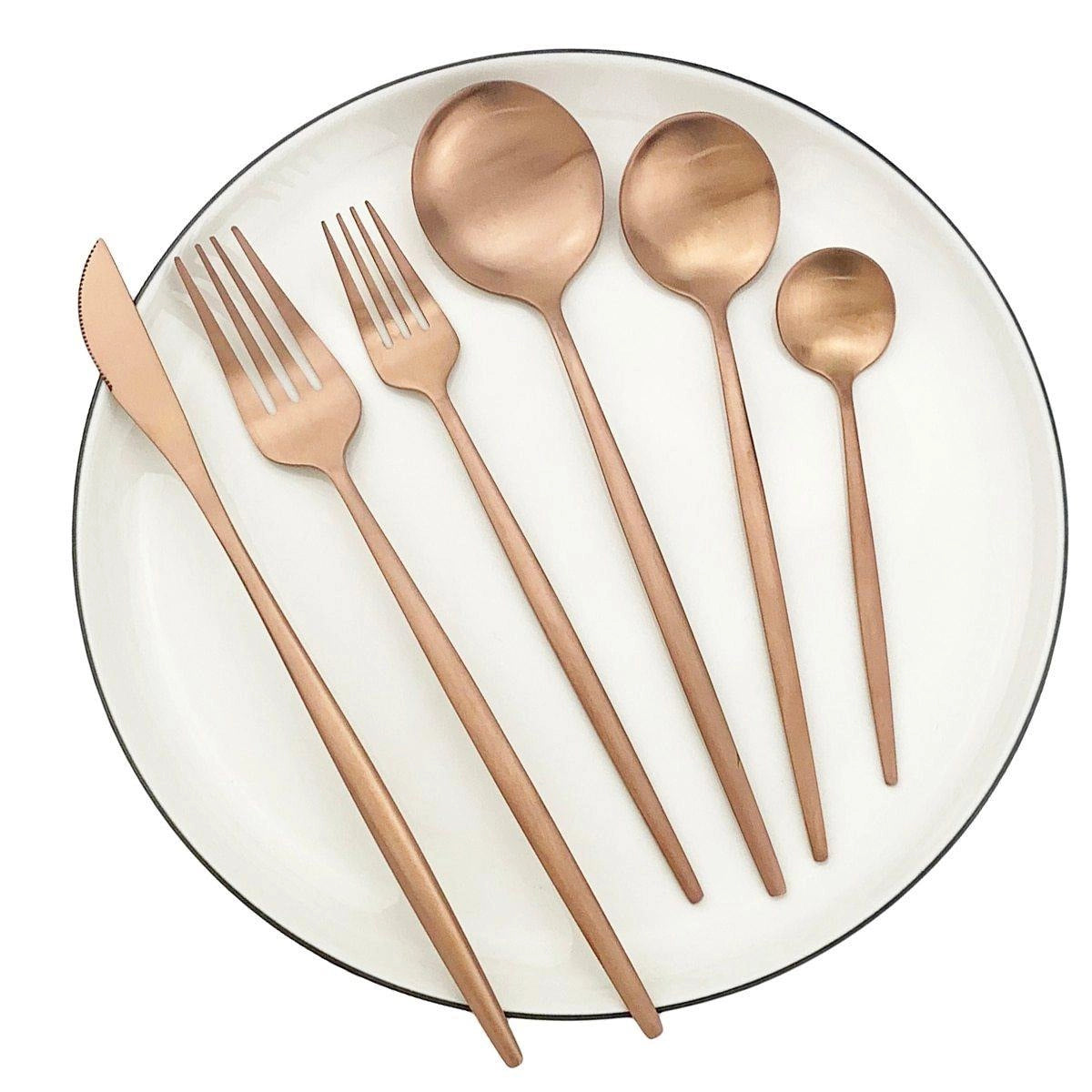 Matte rose stainless steel cutlery set featuring modern minimalist design, elegantly arranged with forks, knives, and spoons, placed on a stylish plate.