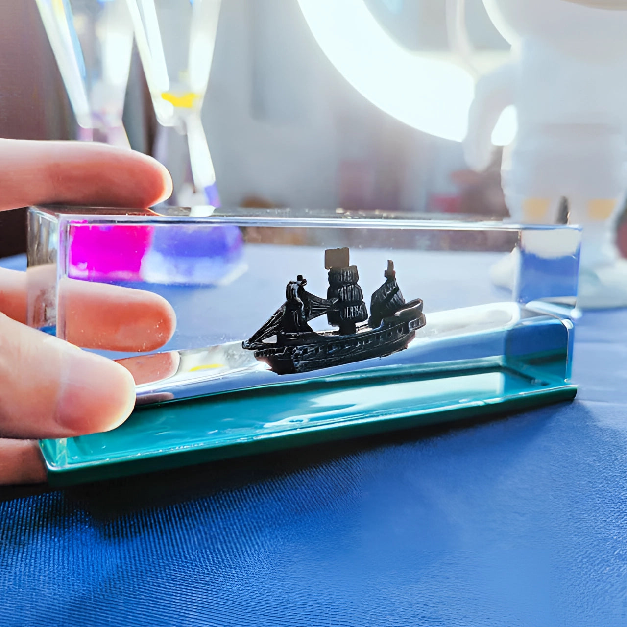 Miniature ship encased in a swirling acrylic wave, featuring electric blue hues, perfect for nautical decor and sea-themed gifts. The detailed model showcases intricate craftsmanship, creating the illusion of the ship sailing through vibrant water.