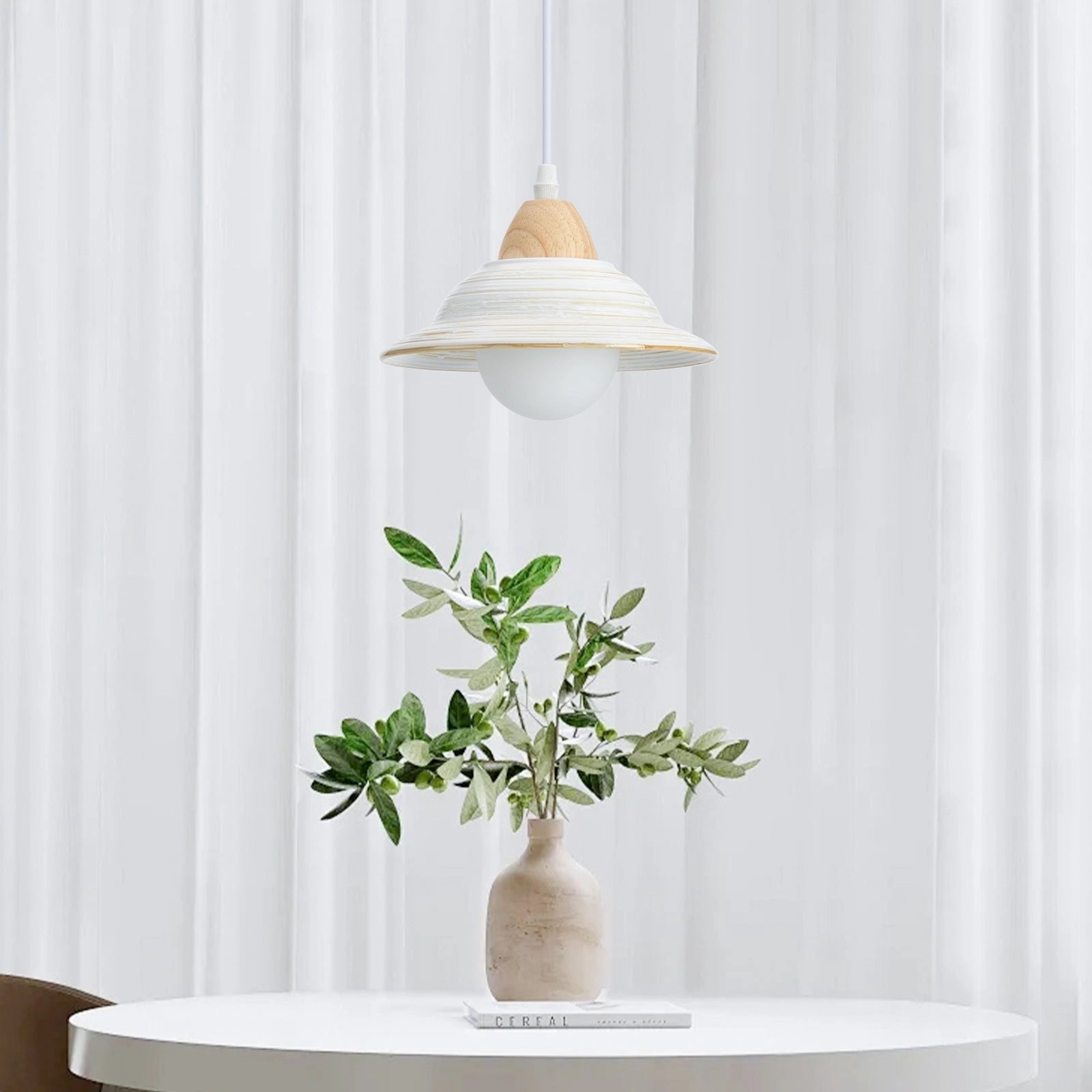 A minimalist Scandinavian wooden pendant light hanging above a Nordic dining table, with a vase and plant on the table, set in a modern interior design setting.