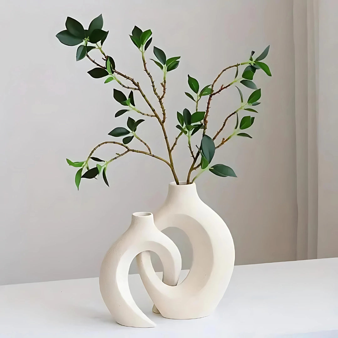 Modern abstract ceramic vase in bohemian style with artistic twig and branch arrangement, placed against a wooden wall, showcasing contemporary home decor.