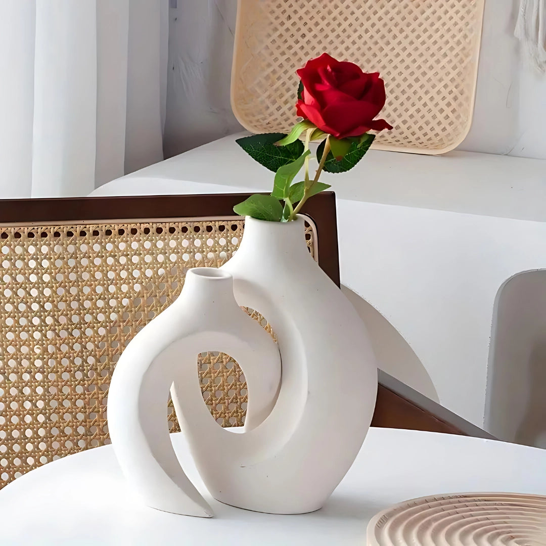 A modern white abstract ceramic vase with a bohemian design, placed on a wooden table in a contemporary home setting, surrounded by subtle interior decor elements.