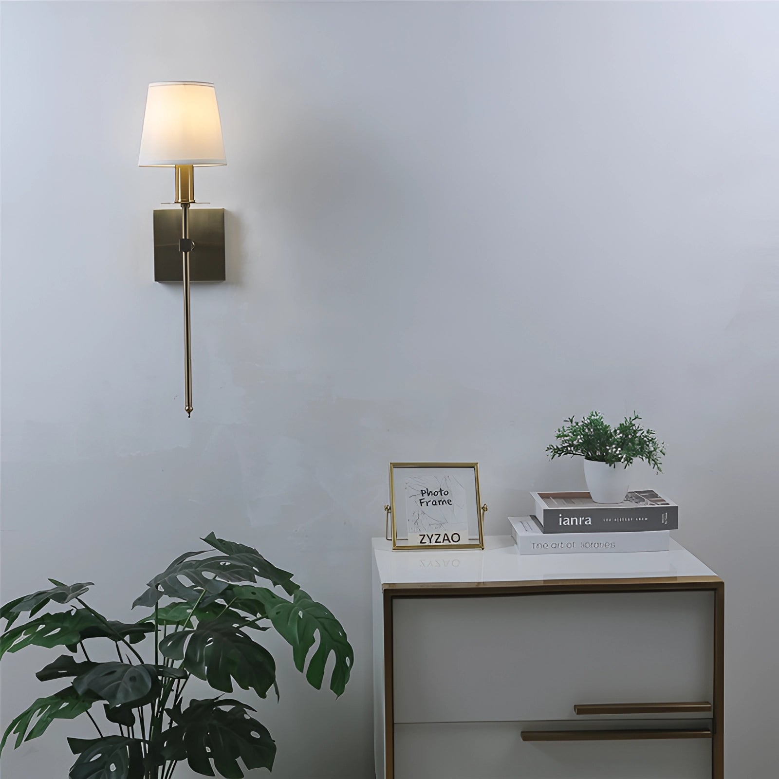 Modern black adjustable wall sconce mounted on a wall, featuring a minimalist design alongside a plant and shelving unit in a contemporary interior setting.