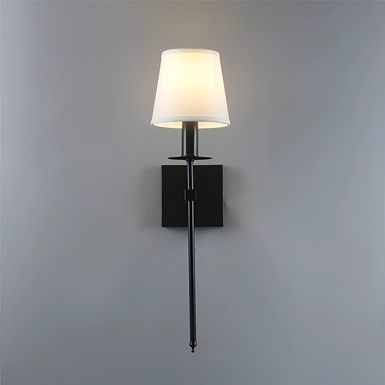 Modern black adjustable wall sconce mounted on a wooden wall, featuring a minimalist design with a metal lampshade, casting light over a nearby table and shelf.