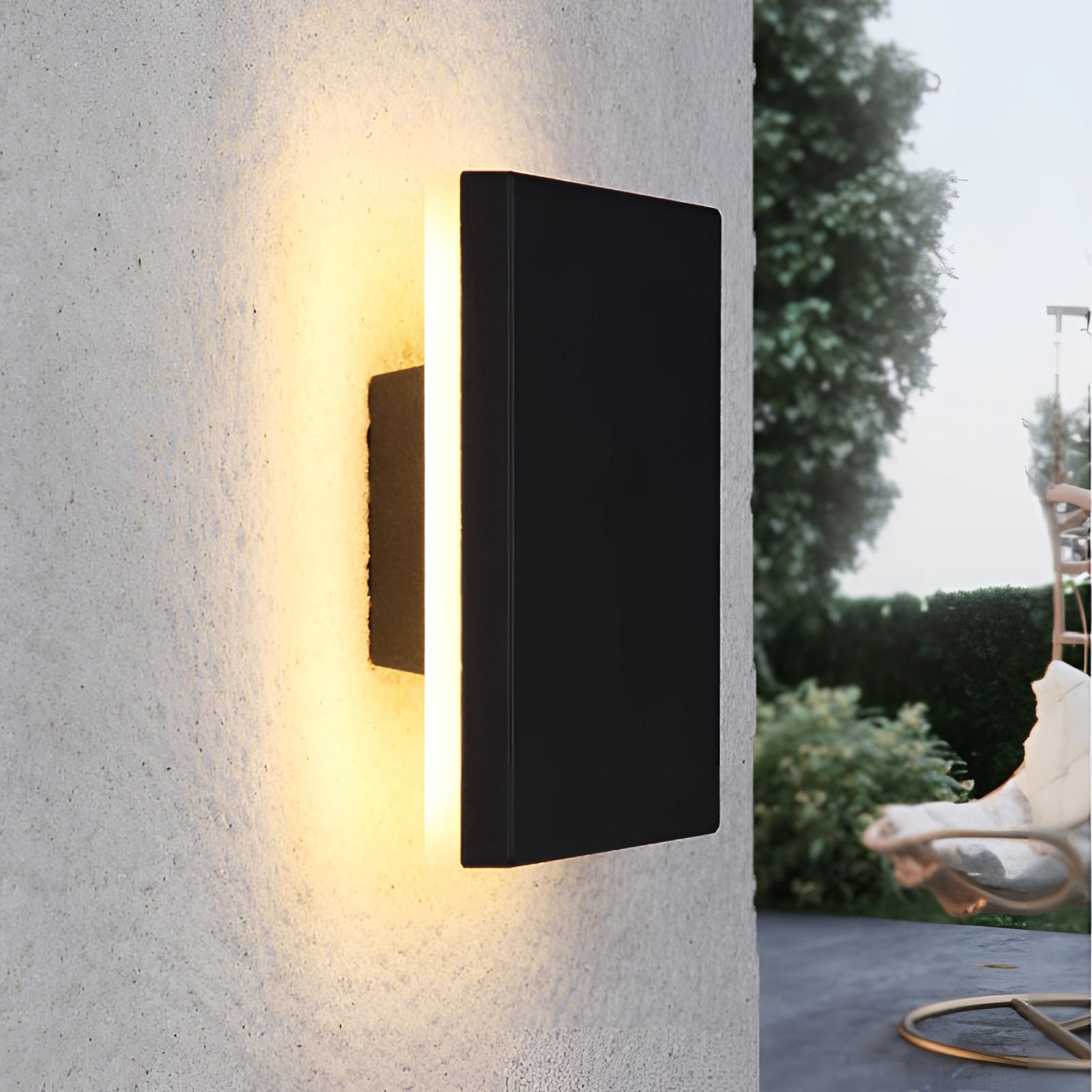 Modern black circular LED wall sconce with a minimalist halo glow design mounted on a wooden panel, surrounded by a tree and a flowerpot, creating a serene and artistic ambiance.