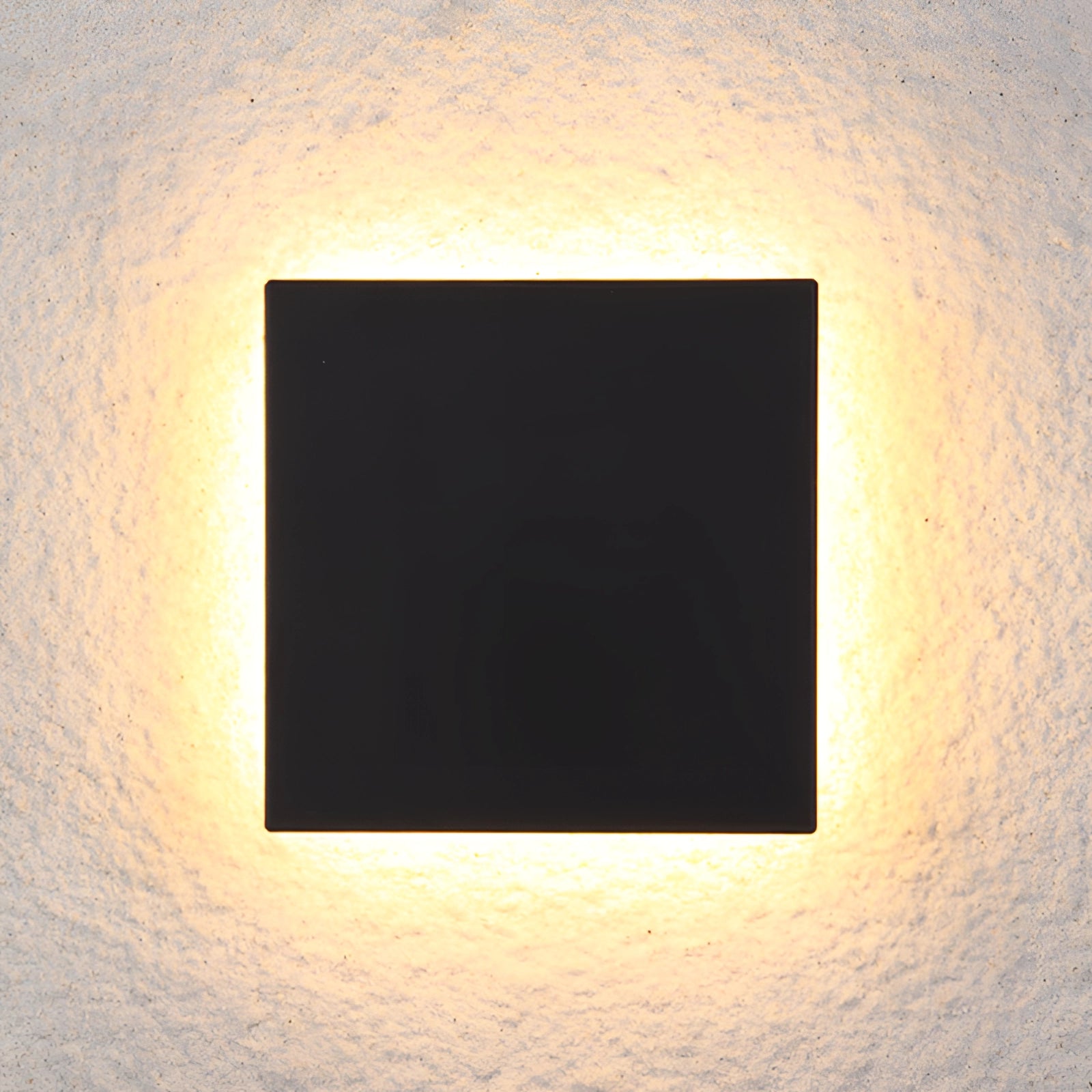 Modern black square LED wall sconce with a minimalist design, featuring a warm amber glow and symmetrical patterns.