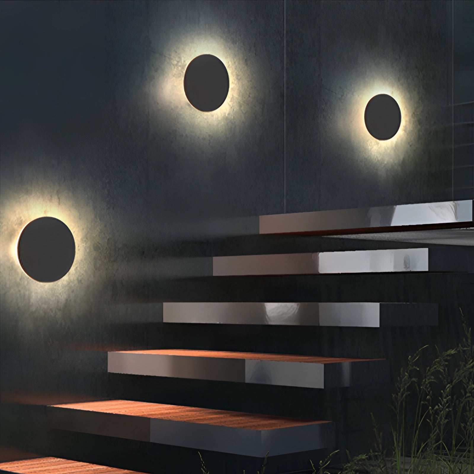 Modern black circular LED wall sconce mounted on a wooden wall, emitting a soft halo glow, with a small plant nearby.