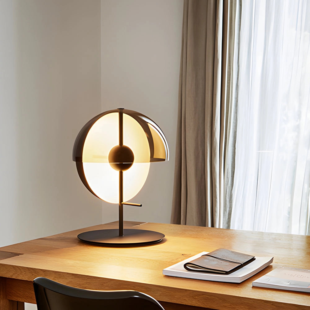 Modern black and gold half-sphere globe desk lamp with adjustable light on a wooden table in a stylish interior setting.