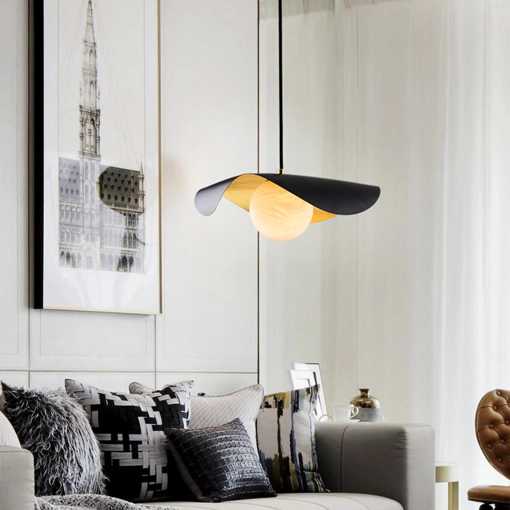 Modern black and gold pendant lights with a contemporary minimalist design hanging in a stylish, comfortable interior space featuring grey furniture and pillows.