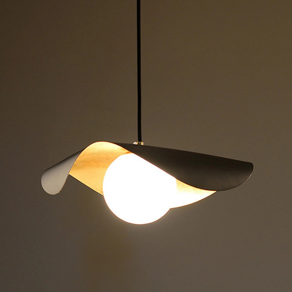 Modern black and gold pendant light hanging from ceiling, illuminating a wooden table below with a contemporary minimalist design.