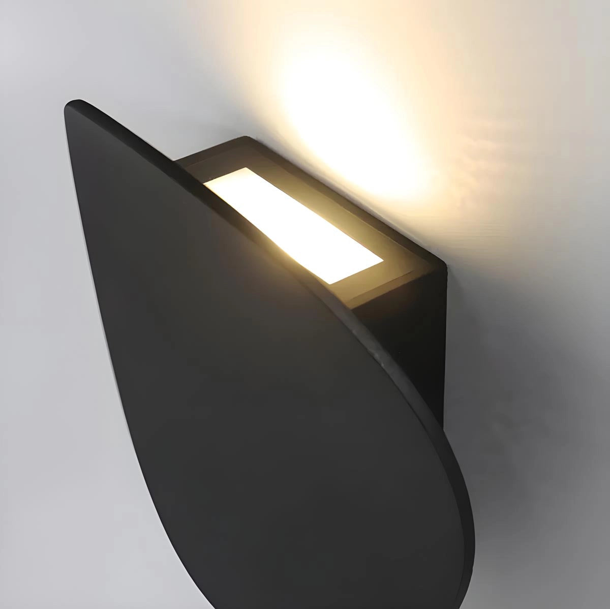 Modern black LED wall light with a minimalist design mounted on a wooden panel, illuminating a room with a soft glow.