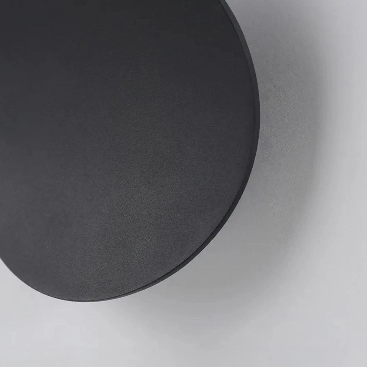 Modern black LED wall light with circular and rectangular elements, featuring a minimalist design and mounted on a wall.