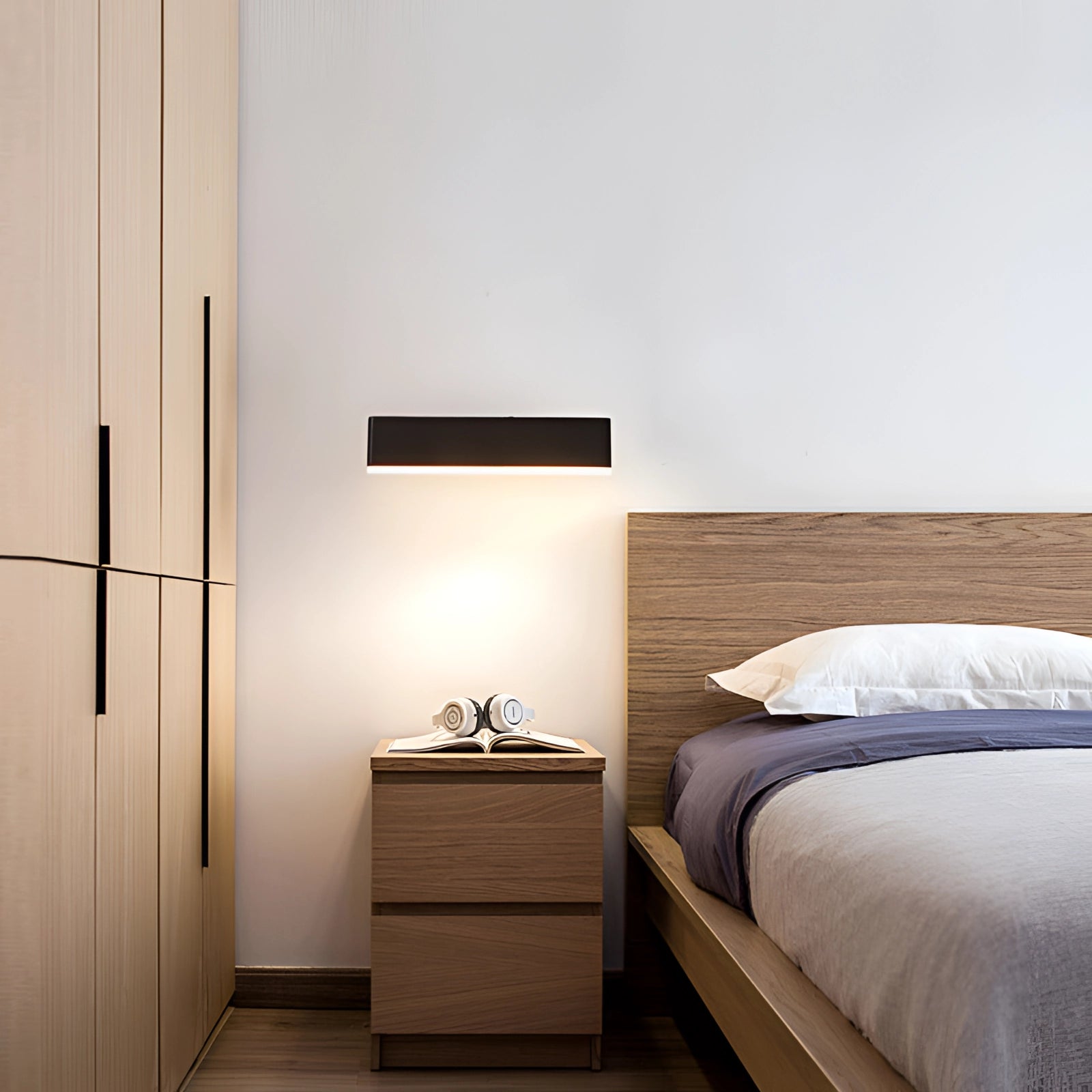 Modern black LED wall sconce with minimalist geometric design mounted on a wooden wall in a contemporary interior setting.