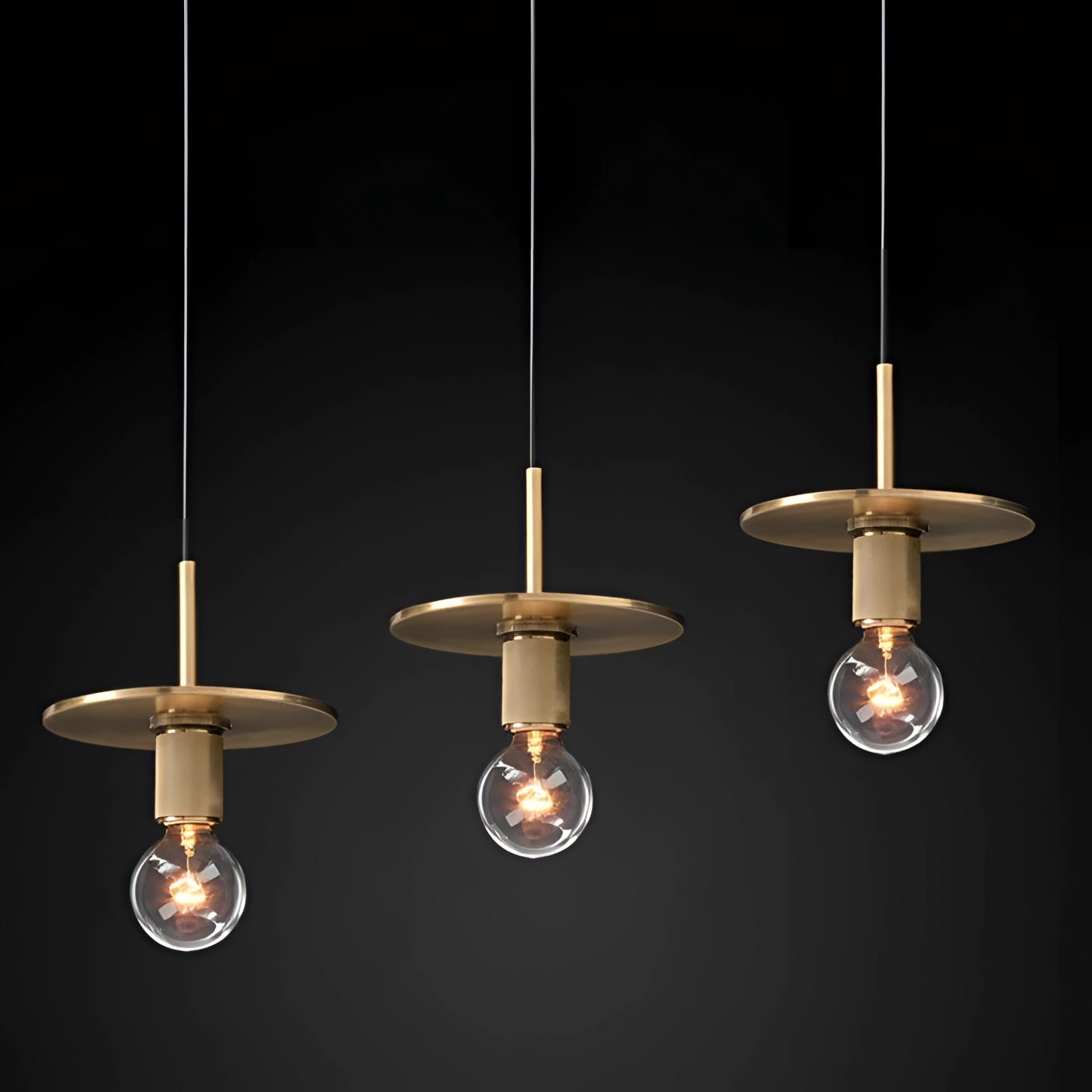 Modern brass finish pendant light with adjustable height, featuring an industrial design. The lamp includes a circular metal shade, visible light bulb, and ceiling fixture.