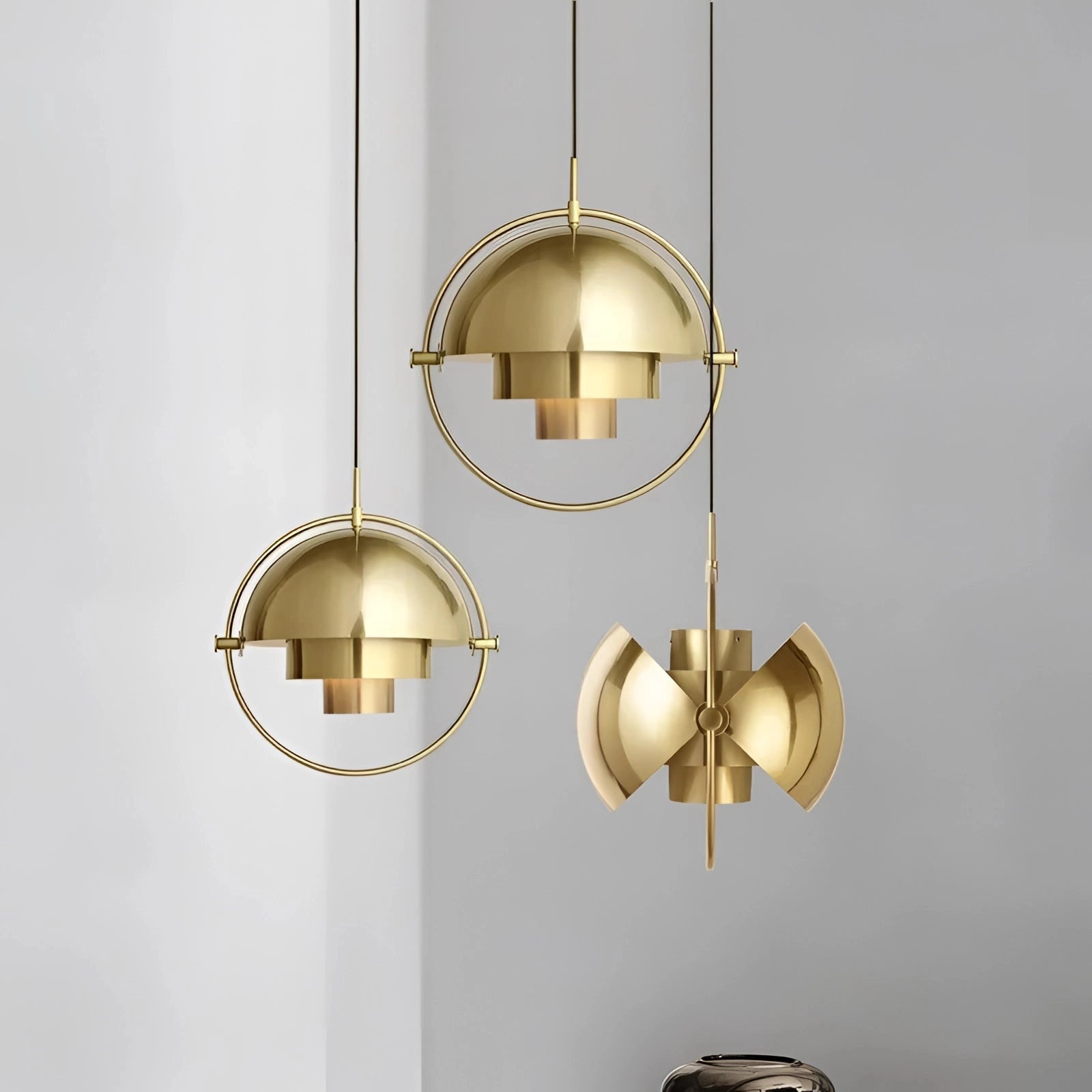 Modern brass finish pendant light with minimalist Scandinavian design, featuring a circular metal ceiling fixture and exposed light bulb.