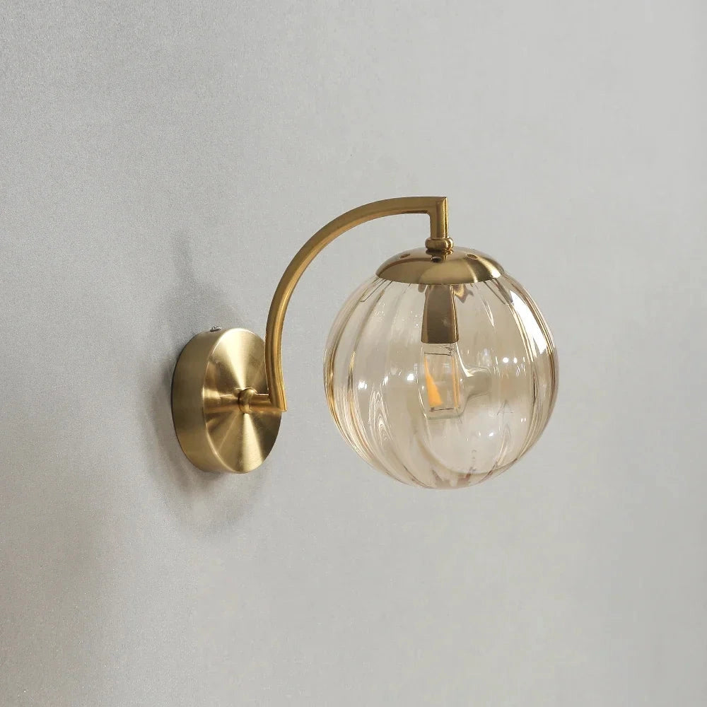 Modern brass globe wall sconce with an amber-toned decorative lamp, featuring a circular design crafted from metal materials, measuring 22.7cm in width.