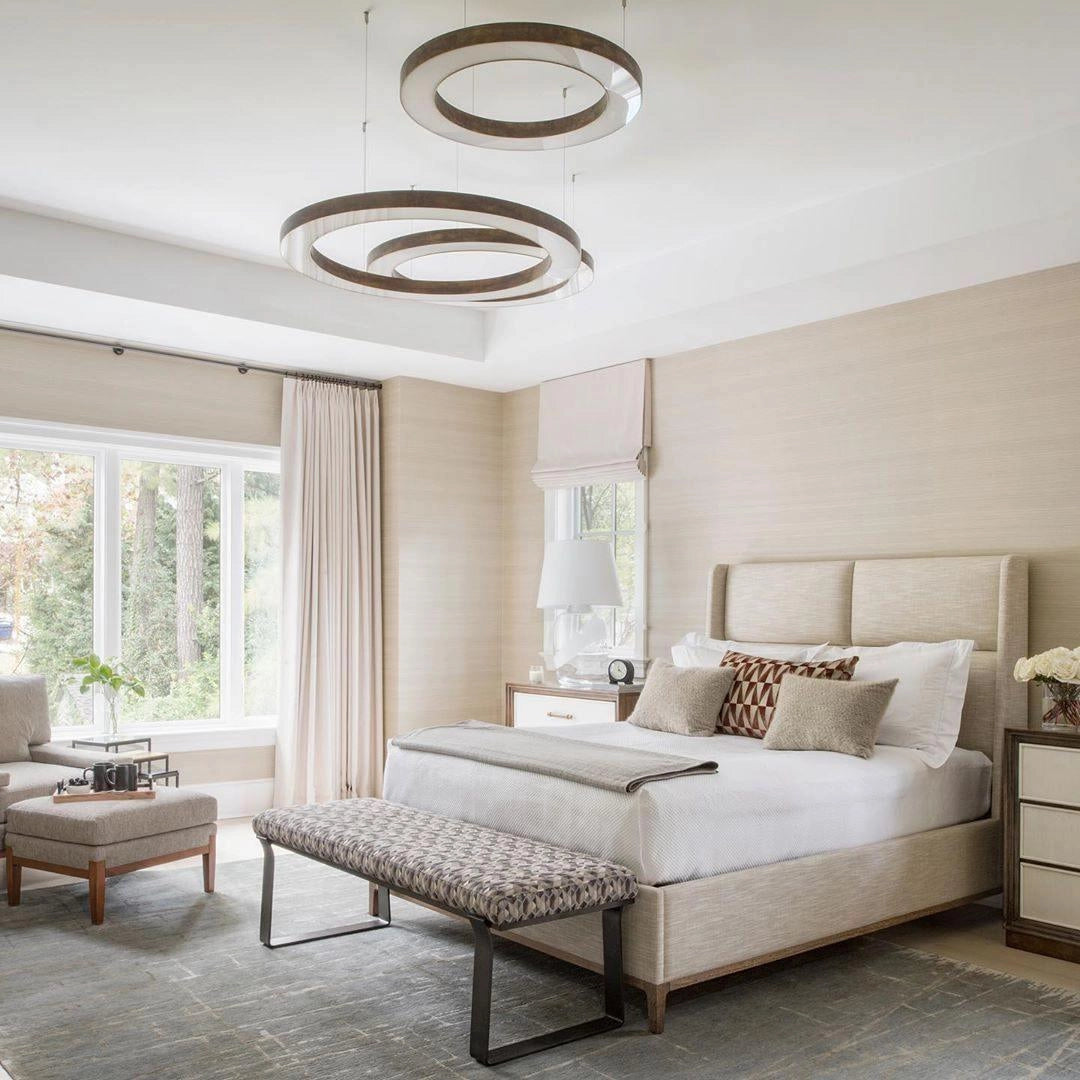 Modern circular LED ring pendant light illuminating a luxury hotel lobby with stylish interior design elements, featuring comfortable seating, wooden accents, large windows, and potted plants.