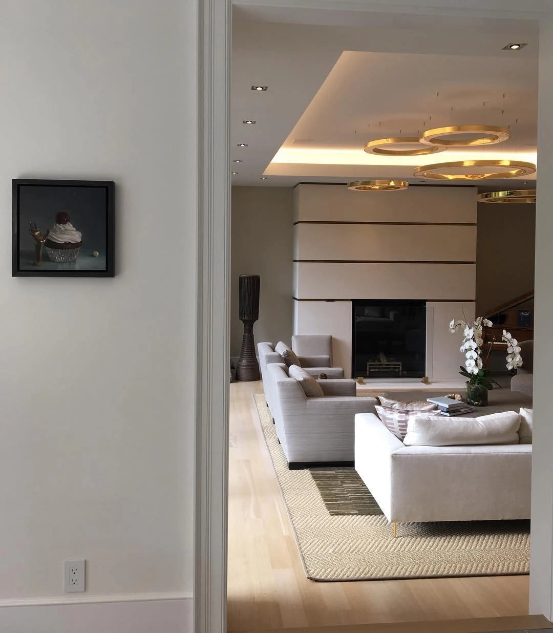 Modern circular LED ring pendant light illuminating a luxury hotel lobby with contemporary interior design, featuring wooden flooring, a sleek countertop, and comfortable seating arrangements like couches and chairs.