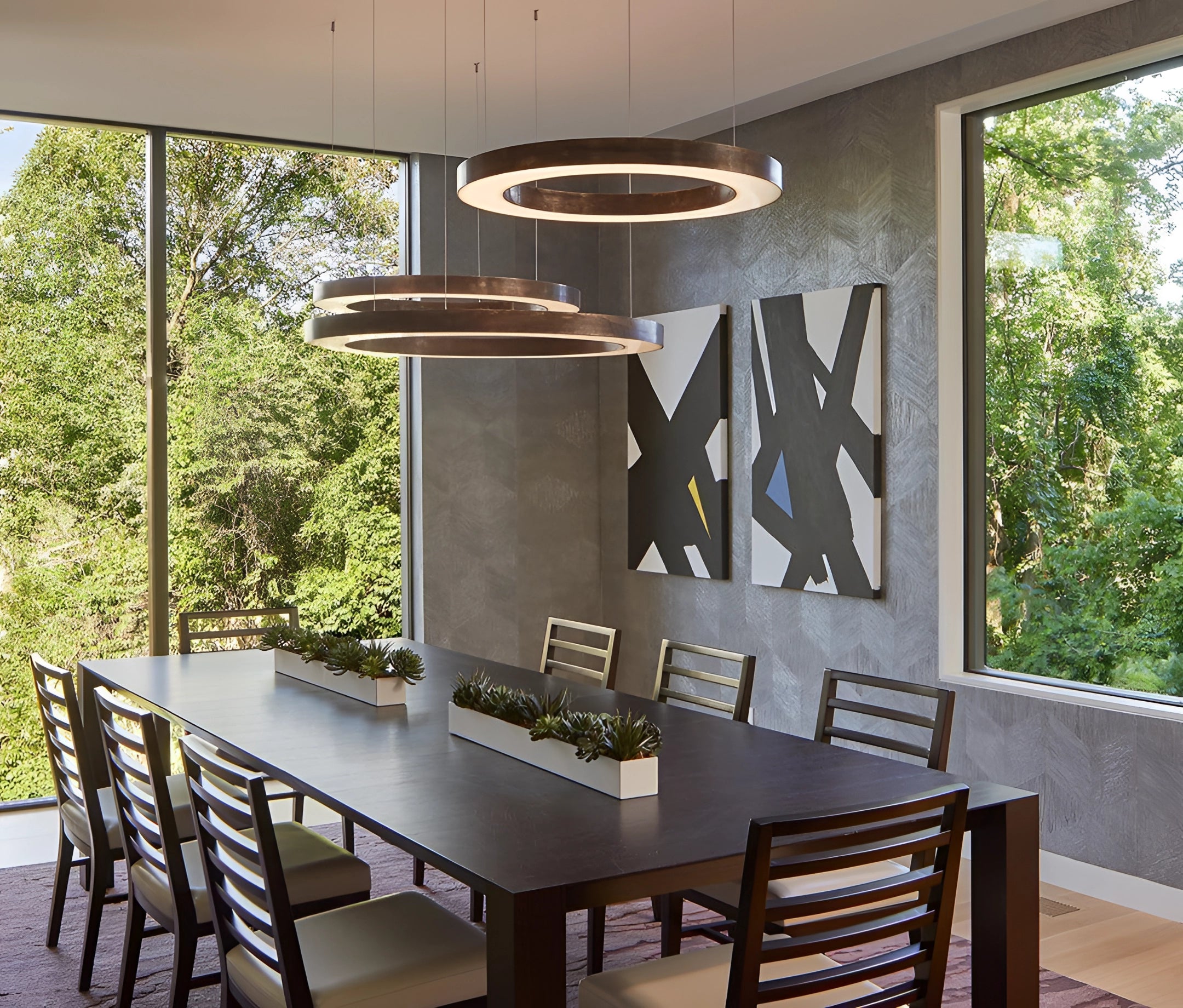 Circular LED ring pendant light hanging in a luxurious hotel lobby setting, featuring modern interior design elements with a wooden table and chairs underneath, creating a sophisticated ambiance.