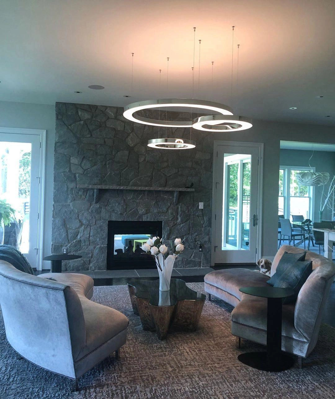 Modern circular LED ring pendant light illuminating a luxury hotel lobby with contemporary interior design elements, featuring a comfortable couch, stylish tables, and large windows that enhance the elegance and ambiance of the space.