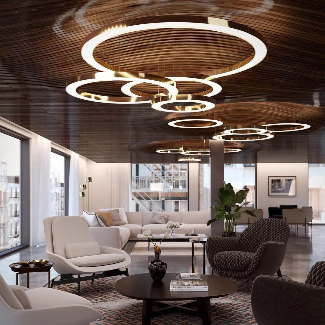 Modern circular LED ring pendant light illuminating a luxury hotel lobby, complementing the contemporary interior design with stylish furniture, including a table and chairs, and decorative plants.