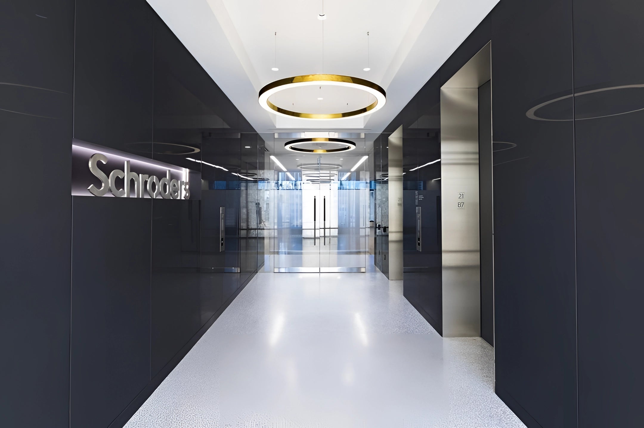 Modern circular LED ring pendant light fixture hanging from a ceiling in a luxurious hotel lobby, showcasing its sleek automotive design and symmetry against a background of tile flooring.