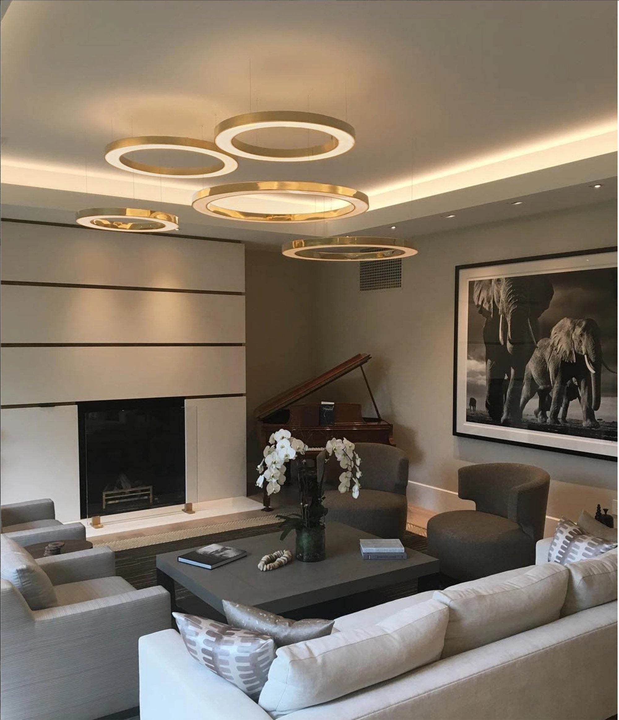 Modern circular LED ring pendant light hanging in a luxurious hotel lobby with sophisticated interior design elements, including a comfortable couch, picture frames on the wall, and a plant enhancing the elegant ambiance.