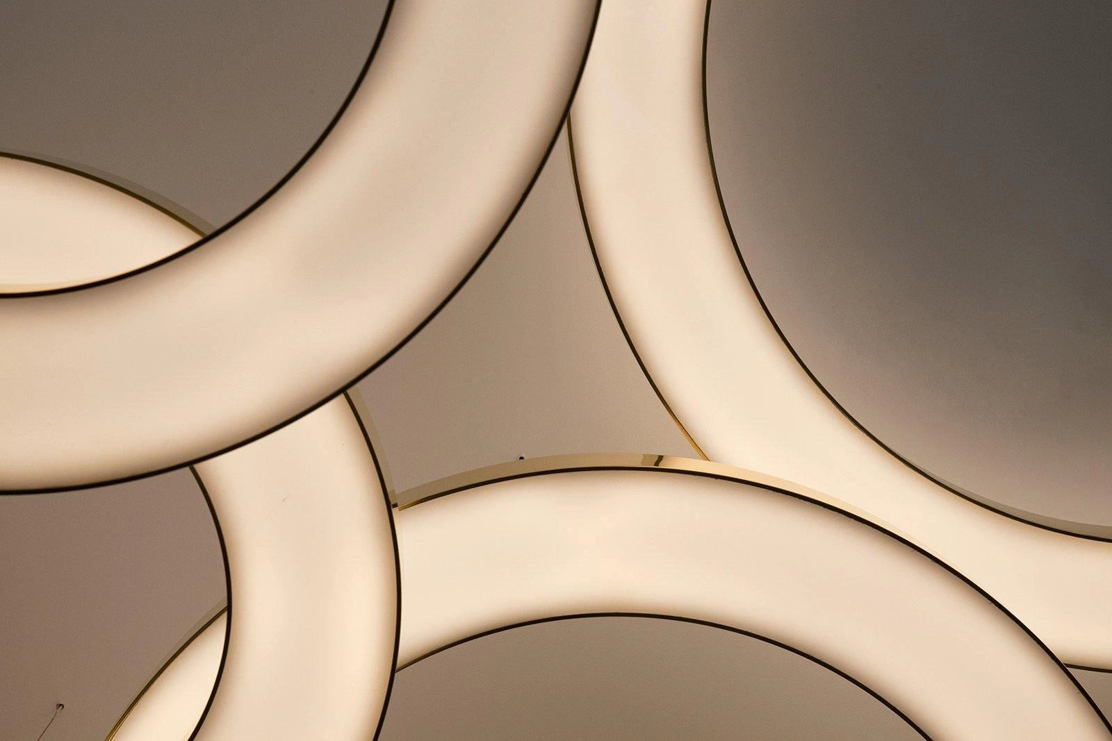 Modern circular LED ring pendant light featuring a luxurious design with a blend of wood and metal materials, showcasing symmetrical patterns and artistic elements, ideal for enhancing the elegance of a hotel lobby.