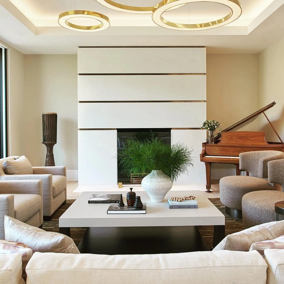 Modern circular LED ring pendant light illuminating a luxury hotel lobby setting with contemporary furniture, including a couch and table, complemented by a plant, all in a sophisticated and comfortable interior design.